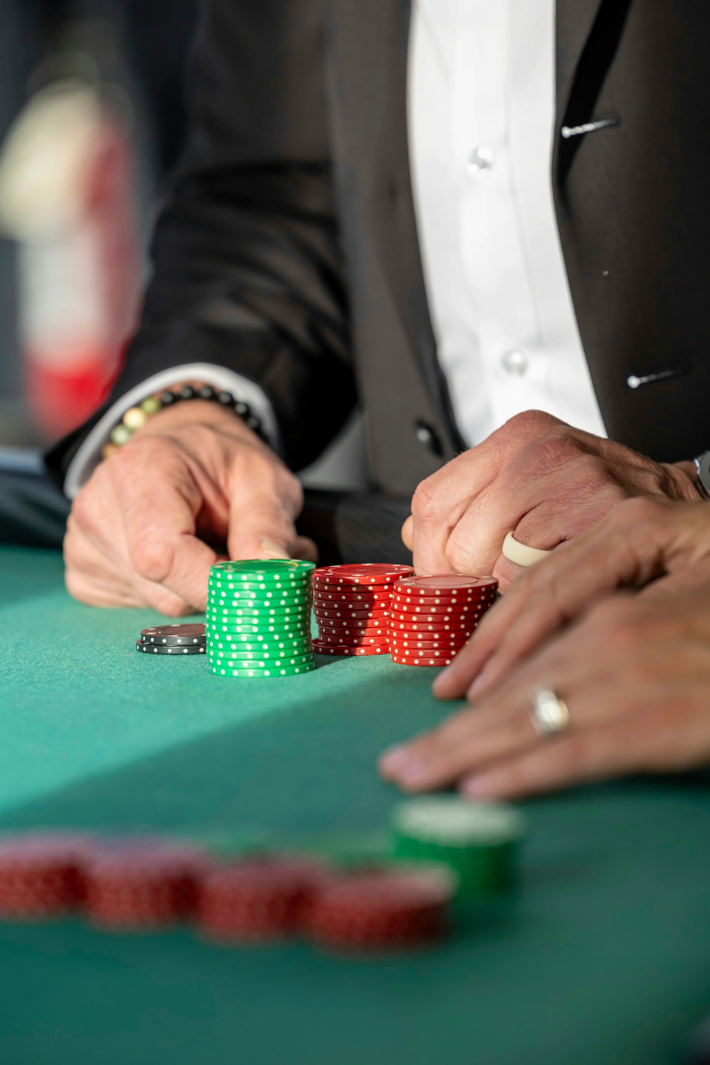 Players' hands and poker chips on a felt table